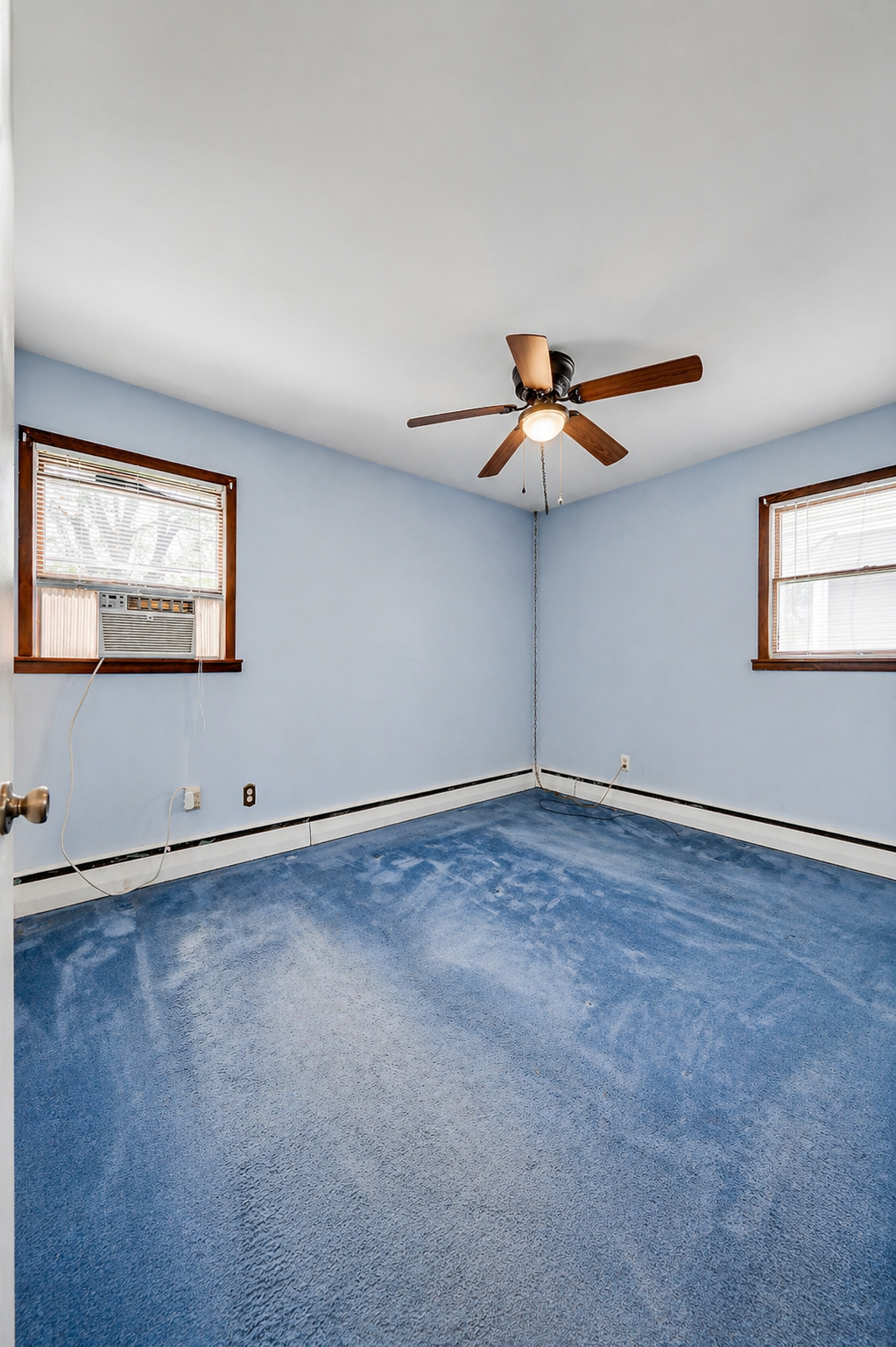 Vacant bedroom with dated blue walls and AC unit