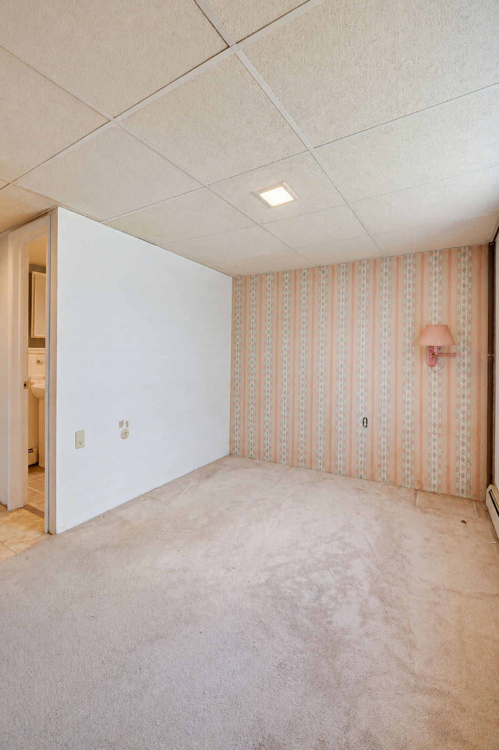 Empty basement room with dated orange wallpaper before virtual remodel